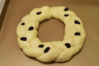 10.	做好的花环面包放在烤盘上，点缀一些黑色的葡萄干