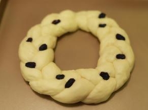 10.	做好的花环面包放在烤盘上，点缀一些黑色的葡萄干