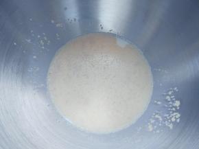 将常温牛奶和酵母粉倒入厨师机桶内