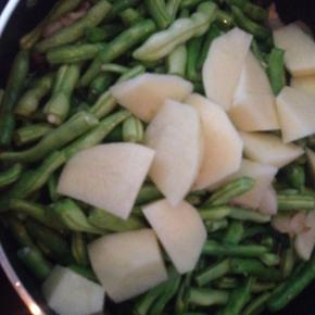 豆角变色后，加入土豆块翻炒。