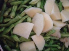 豆角变色后，加入土豆块翻炒。