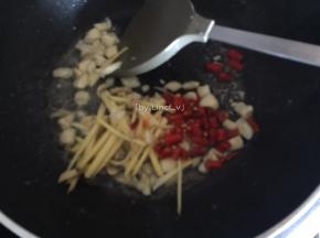 接着将油倒出，留一点底油。放入大蒜、姜丝、小红椒爆香