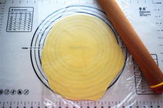 将面团放入两层保鲜纸中间，擀开成2毫米厚的圆形面片。