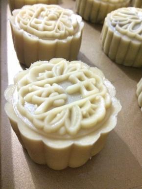 取一面皮，捏成饼状，中间放上莲蓉球，往上轻推包好，用月饼模具压出形状