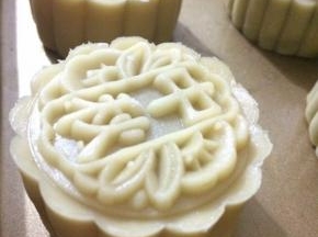 取一面皮，捏成饼状，中间放上莲蓉球，往上轻推包好，用月饼模具压出形状