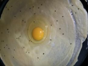 等到略有凝固时加入几颗芝麻、再打入一个鸡蛋