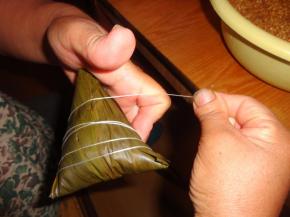 折叠粽叶使粽叶把米全部包住。用棉线缠绕粽子4―5圈，系上活扣，吃粽子的时候方便解开。