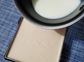 待牛奶降到手温时，取出凝固好的蛋糕，把牛奶倒入，填满慕斯圈，再次放入冰箱凝固。