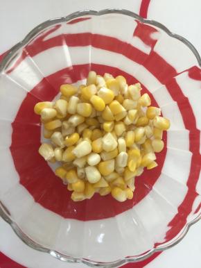 取一干净大碗，先放入蒸熟了的玉米粒