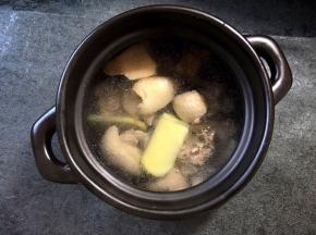 加入200毫升的开水，淹没过鸭块即可将大蒜生姜放入煲中