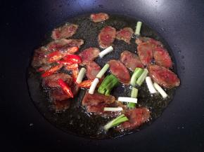 接着放入小红尖椒和蒜苗头翻炒均匀。