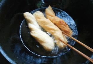 面胚定型后用中火，用筷子压住翻滚油条，使各面炸透。