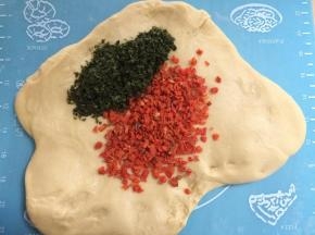 将面团擀成片，把胡萝卜碎和海苔碎撒在上面