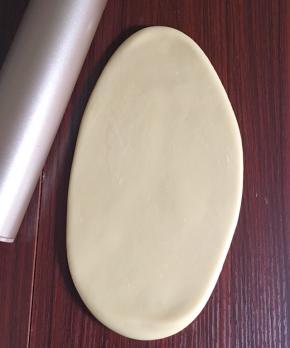 包裹好，捏紧封口，收口朝下，然后用擀面杖慢慢擀成椭圆形