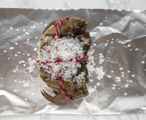 将锡纸裁成长30厘米、宽15厘米的长方形，放上螃蟹，在背上撒上海盐。