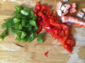 将青椒、红椒焯水后与肉蟹棒一起切丁待用