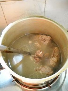 炒好的脊骨移入高压锅内，加入适量温水，大火煮开。