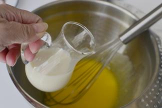 蛋黄里面加入玉米油搅拌顺滑加入糖、豆浆继续拌匀