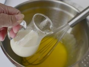 蛋黄里面加入玉米油搅拌顺滑加入糖、豆浆继续拌匀