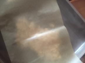 倒入准备好的铺了油布的烤盘里，上面加盖油纸，用擀面杖擀薄