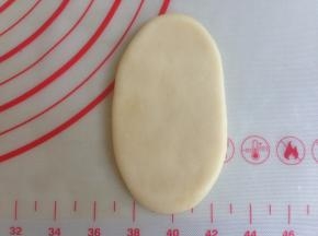 将松驰后的油酥皮压扁，用擀面棍擀成牛舌状