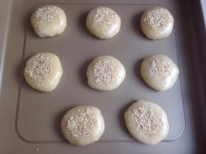 用虎口收口，搓圆，放在不粘烤盘上，压扁。如果你想老婆饼更扁平的形状，可以先在案板上用擀面棍擀平再放烤盘上。表面刷蛋液，撒芝麻