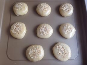 用虎口收口，搓圆，放在不粘烤盘上，压扁。如果你想老婆饼更扁平的形状，可以先在案板上用擀面棍擀平再放烤盘上。表面刷蛋液，撒芝麻