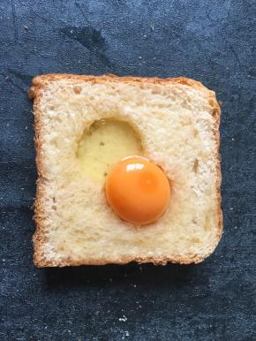 将鸡蛋打入洞中多余的蛋清淋在周边面包上