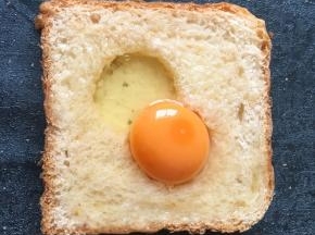 将鸡蛋打入洞中多余的蛋清淋在周边面包上