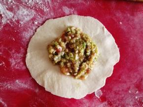 7.	把面团擀成圆盘状，放入适量的馅料，