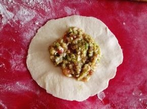 7.	把面团擀成圆盘状，放入适量的馅料，