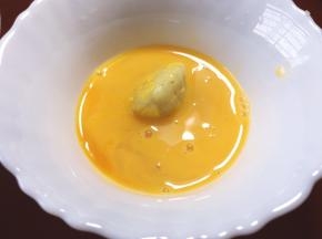 将整形后的土豆窝窝头放入蛋液滚一圈，让其均匀沾满蛋液