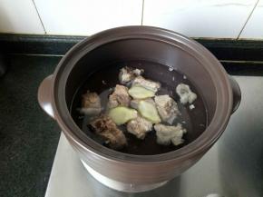 锅里添水，没过排骨，放几片姜片，大火煮开小火煲。