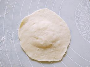 用擀面杖擀成中间厚周围薄的圆片