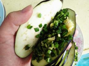 5.	拿一个切好的茄子片，从中间打开，放入适量韭菜鸡蛋馅，