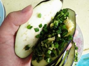 5.	拿一个切好的茄子片，从中间打开，放入适量韭菜鸡蛋馅，