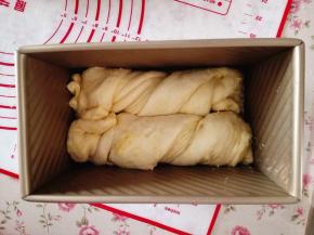 15.	取一条，扭一下，放入吐司盒里，另一条也如此操作，