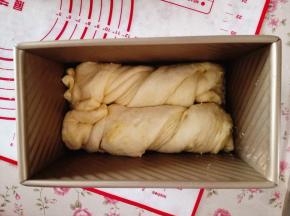15.	取一条，扭一下，放入吐司盒里，另一条也如此操作，