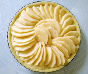 将苹果去皮去核切片，均匀铺在内陷上，在表面抹融化的黄油