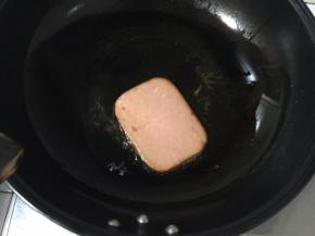 锅中放入少许玉米油，开小火，火腿肠切片，放入锅中煎，这时将生菜叶洗干净备用