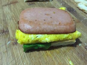 拿一片吐司，依次放上生菜叶，鸡蛋，火腿肠，再放上另一片吐司，就可以了，从中间切半