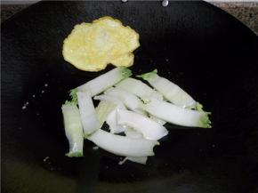 将鸡蛋反面煎好后铲在锅边，放切好的白菜杆，炒软。