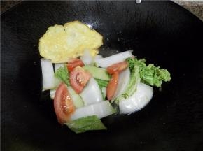 倒入白菜叶和番茄块炒均匀。