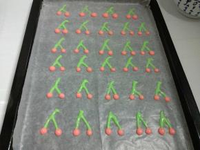提前预热烤箱180度，烤盘铺好油纸，裱花袋剪个小口，画出樱桃的图案。放入预热烤箱，烤1分钟定型。