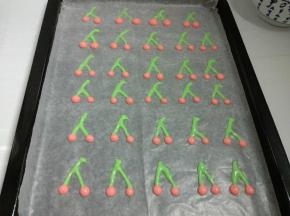 提前预热烤箱180度，烤盘铺好油纸，裱花袋剪个小口，画出樱桃的图案。放入预热烤箱，烤1分钟定型。