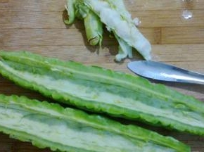 苦瓜剖开两半，用勺背把中间的白瓤去掉。