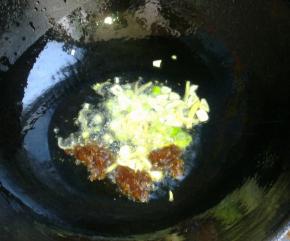 锅里倒油，冷油下入葱姜蒜和郫县豆瓣酱炸香。