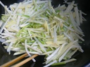 锅里中火爆香葱蒜。倒入土豆丝和尖椒一起翻炒。