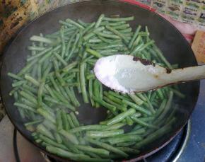 加入适量盐煸炒至长豆角表皮变皱。