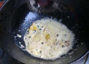 另取一个锅，倒入少量油，下入咸蛋黄泥炒至起大泡。